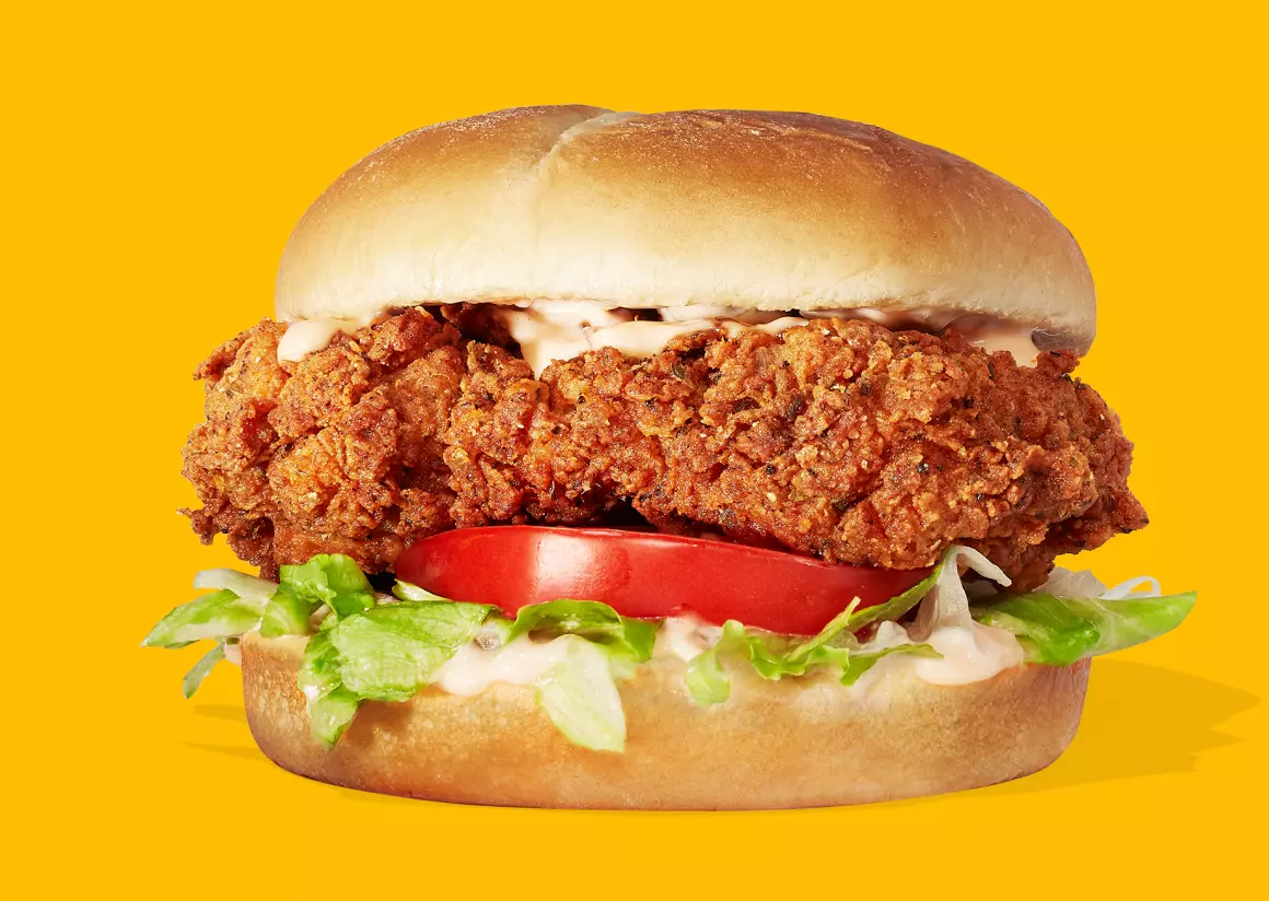 A fried chicken sandwich on a yellow background.