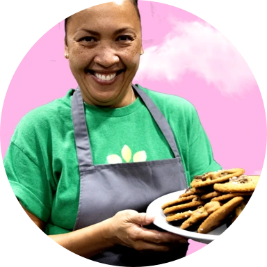 A smiling woman holding a plate of cookies.